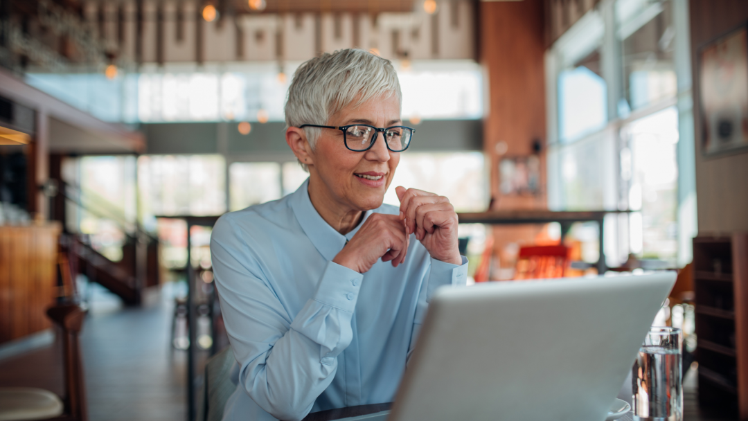 Smiling older businesswoman on a laptop, symbolizing confident exit planning and retirement security.
