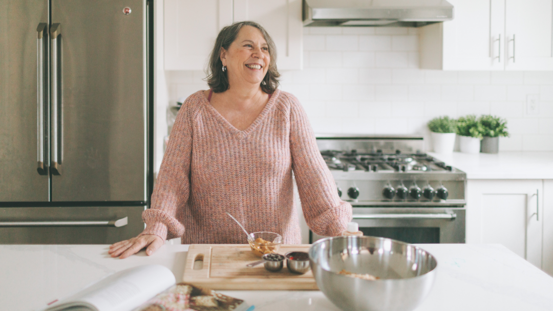 Smiling older woman in a bright kitchen, symbolizing retirement planning and lifestyle confidence.