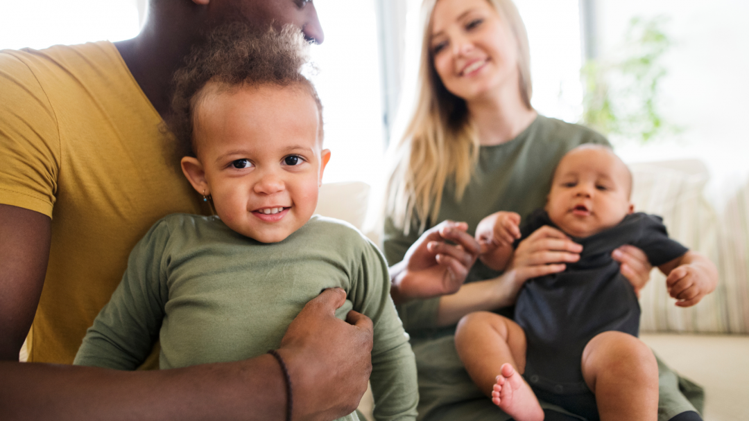 Young family with two children smiling together, symbolizing financial planning for the future.
