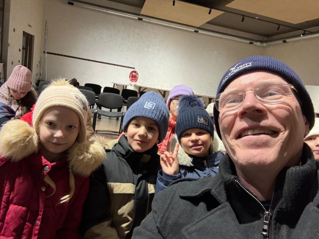 Michael Brady of Generosity Wealth Management takes a selfie with children attending Frontier Horizon's Winter Camp Dreamland in Ukraine, where displaced youth experience friendship, encouragement, and a sense of normalcy.