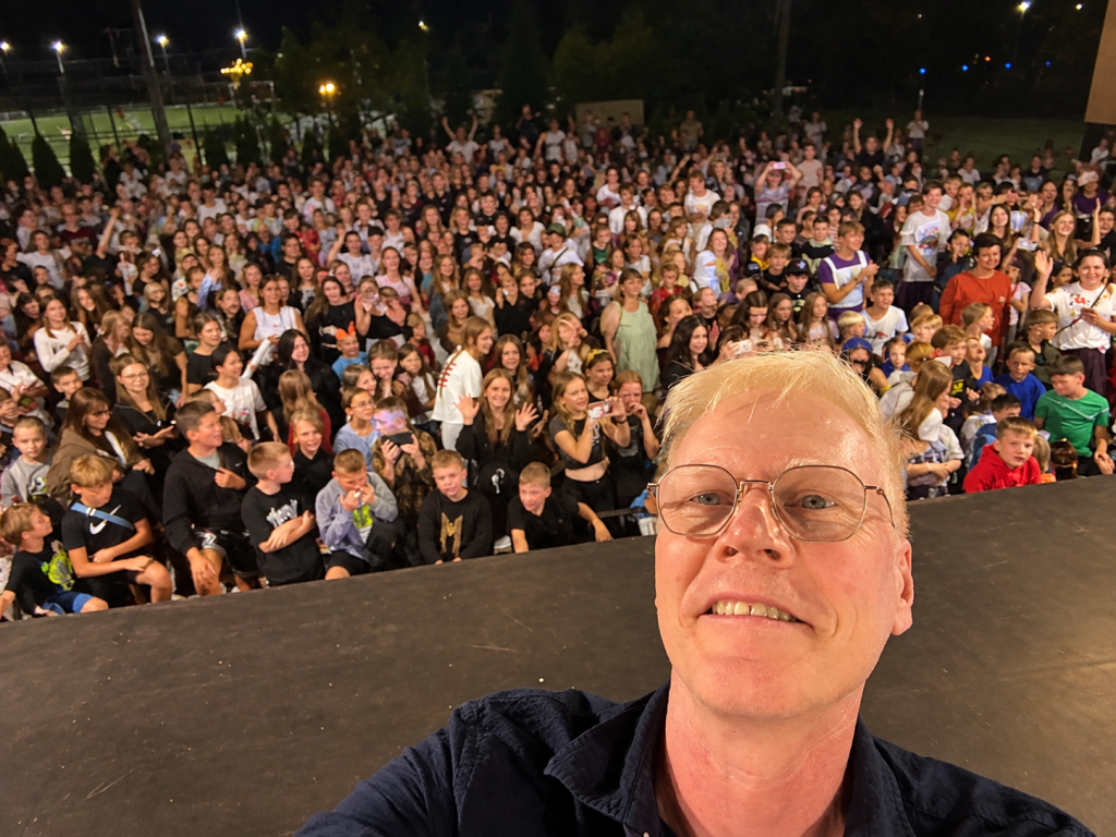Michael Brady takes a selfie from the stage with children and teens gathered at Camp Dreamland 2026 in Ukraine.